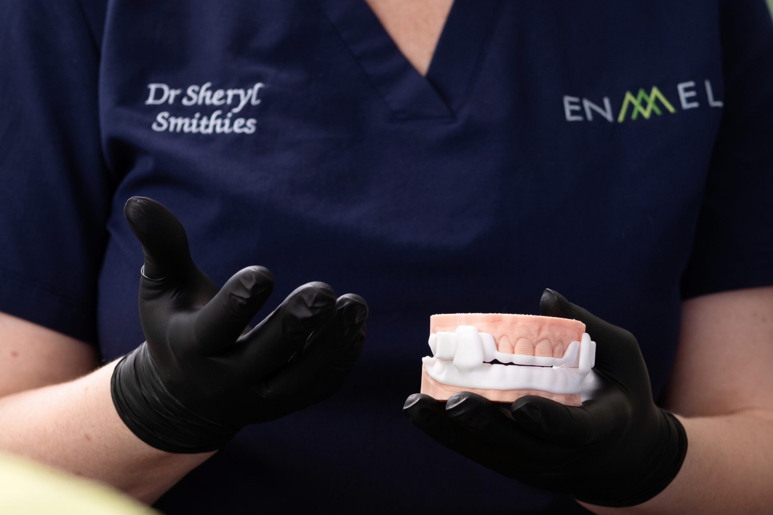 Practitioner holding a dental arch model fitted with a custom oral appliance for airway alignment.