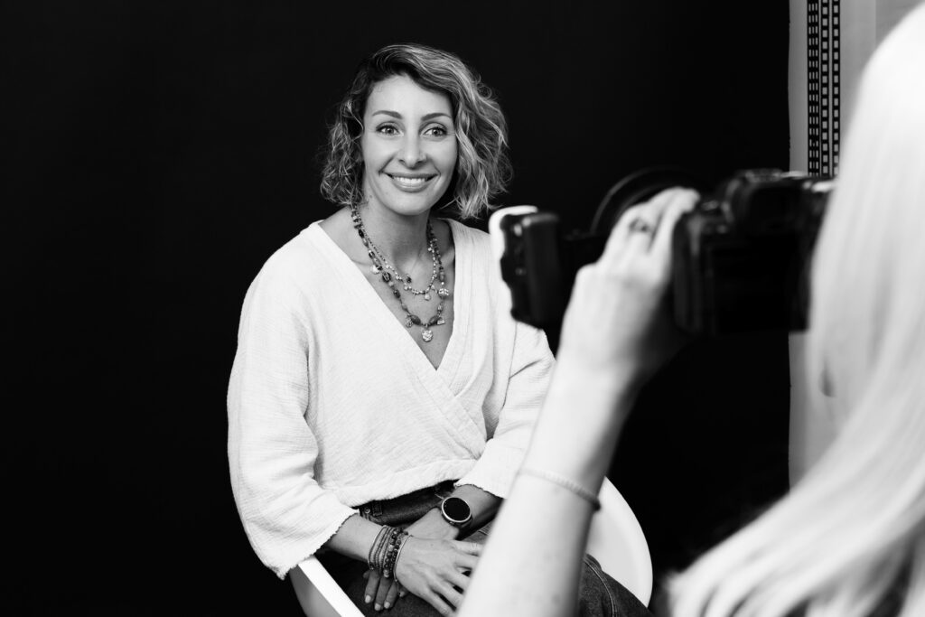 A female patient smiling naturally while sitting for a portrait shoot following cosmetic dental work.