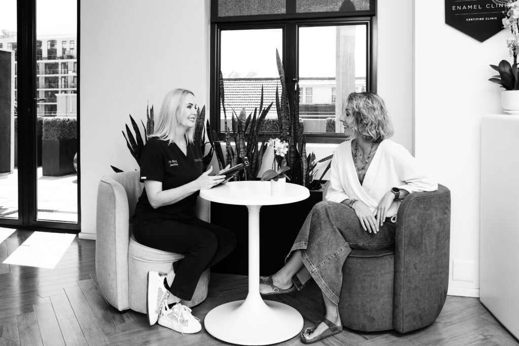 Dr Sheryl Smithies discussing a personalized treatment plan with a patient seated in a comfortable clinic lounge.